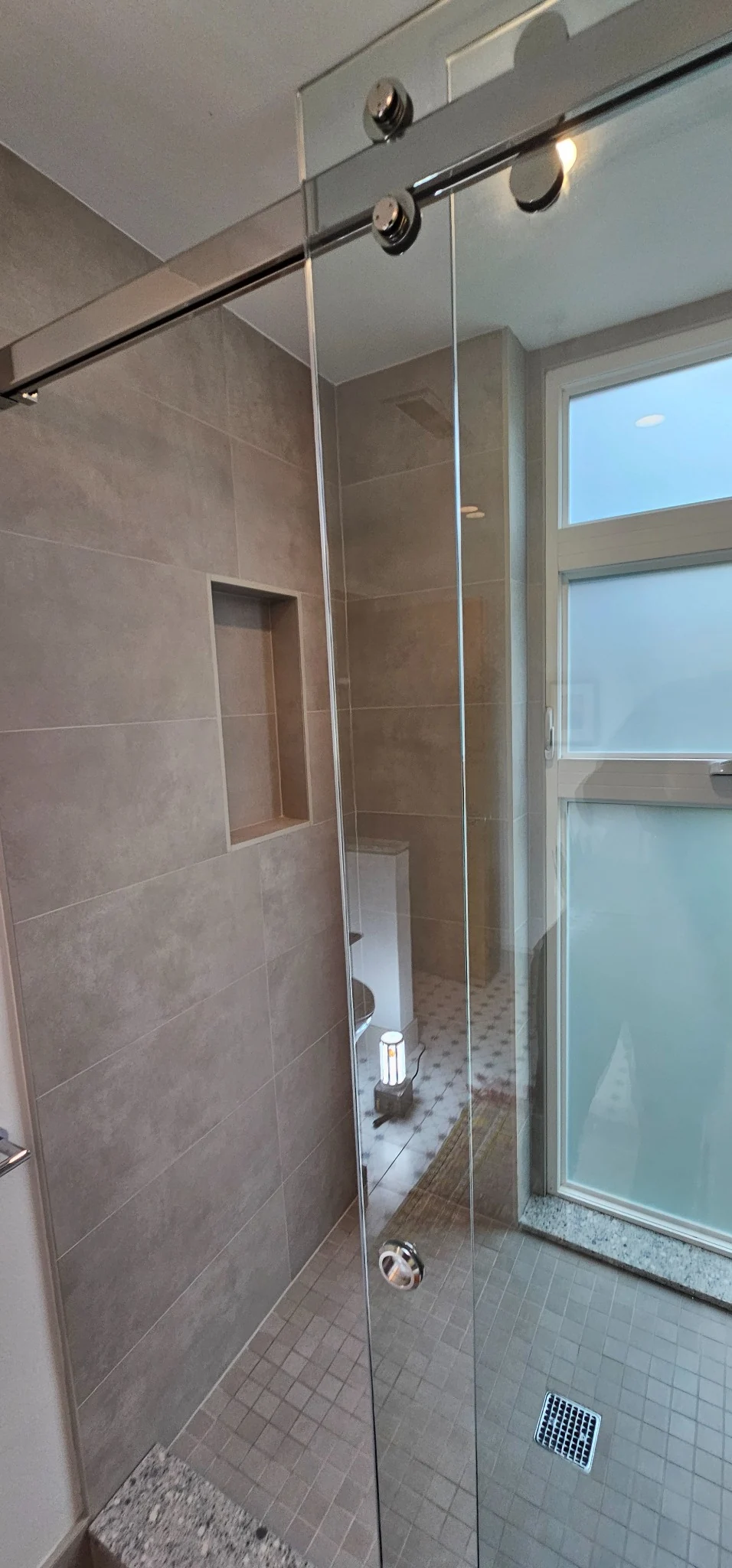 Tiled shower with glass panel and daylight from the window