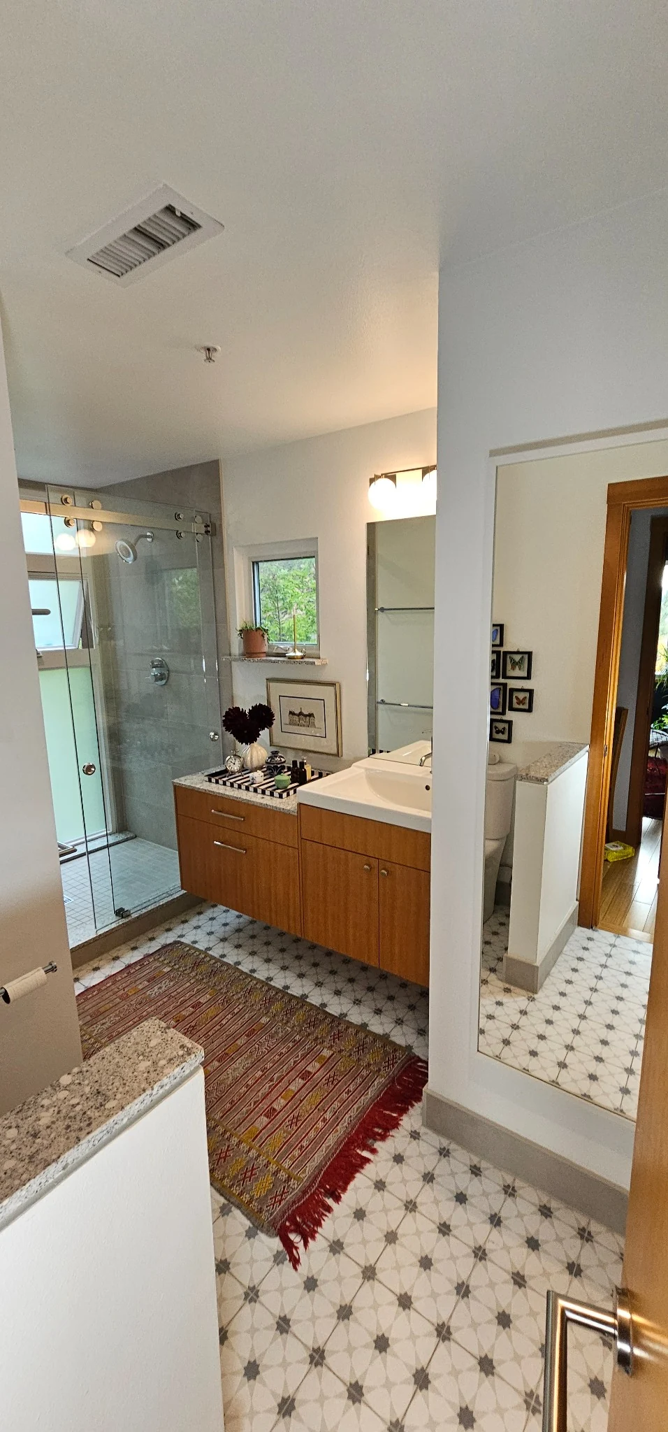 Full bathroom showing the shower, double vanity and patterned floor