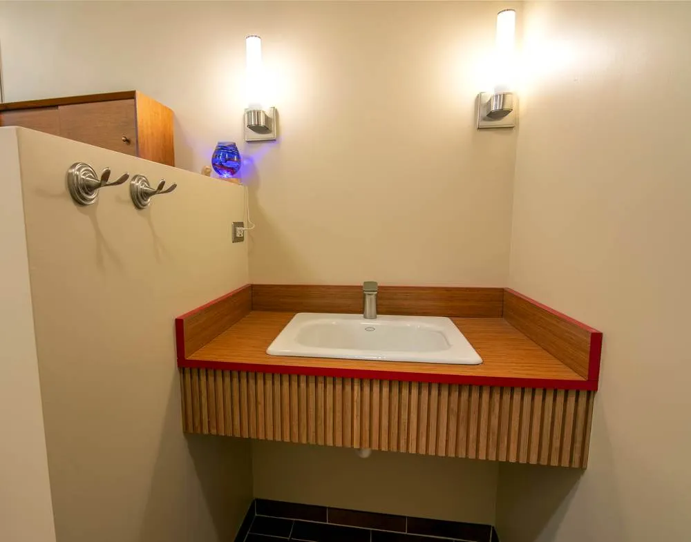 Custom vanity in the Greenwood bathroom with warm wood finish and integrated sink