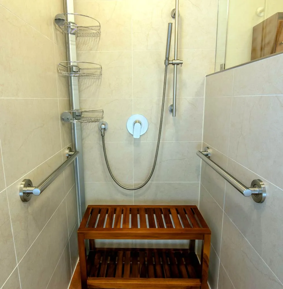 Curbless shower area with grab bars, bench, and tile surround in the Greenwood bathroom renovation