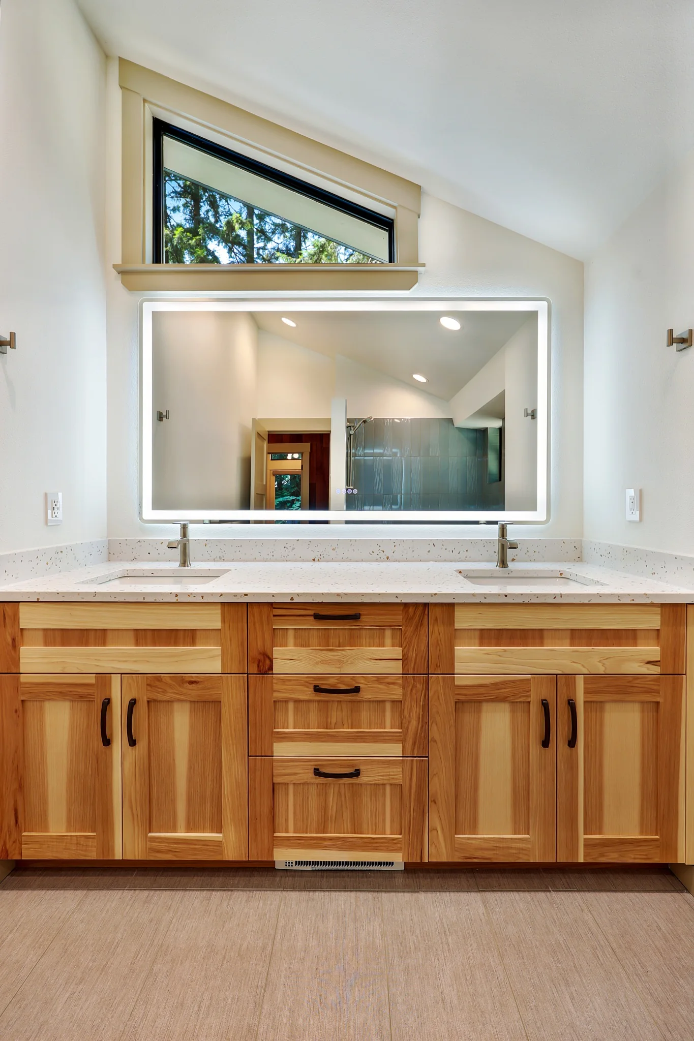 Bathroom with wood vanity, wide mirror, and high window