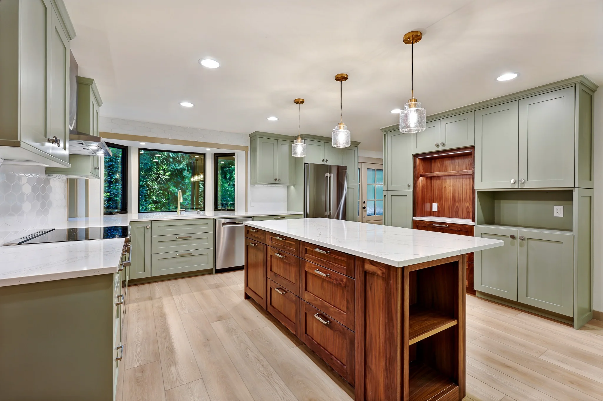 Green kitchen cabinetry, wood island, and large window over the sink