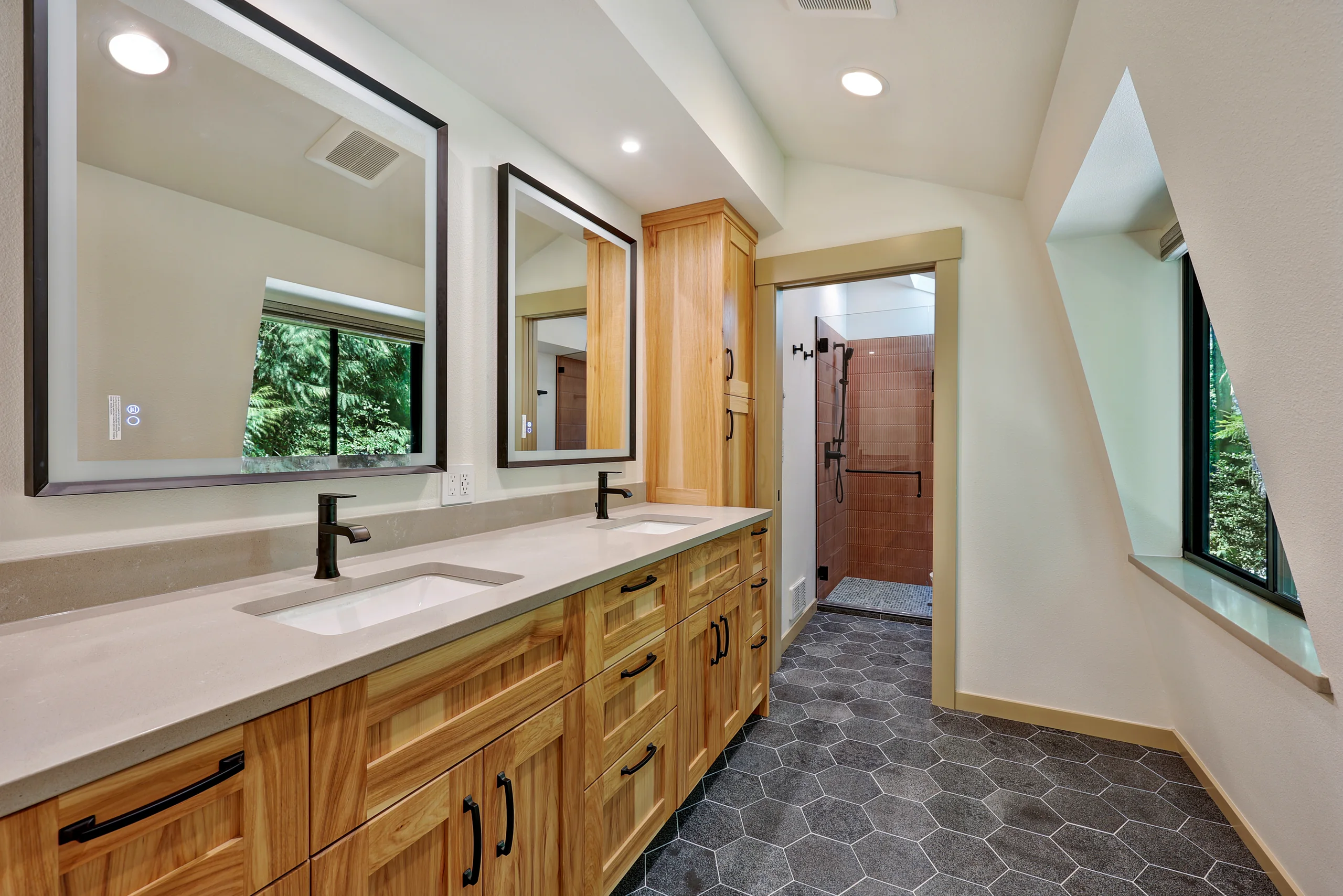 Double vanity with wood cabinetry and dark tile floor