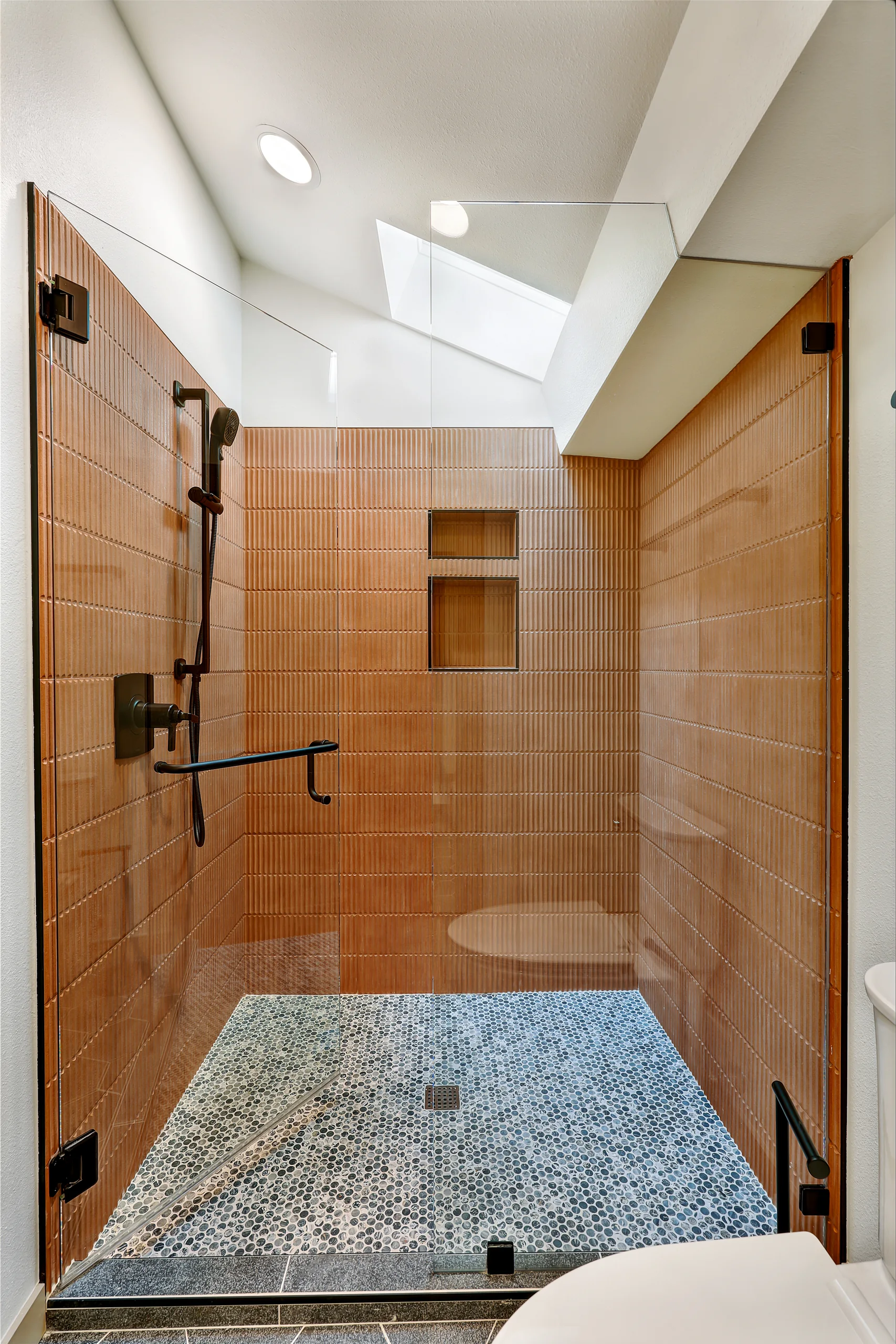 Walk-in shower with wood-look wall tile and pebble floor