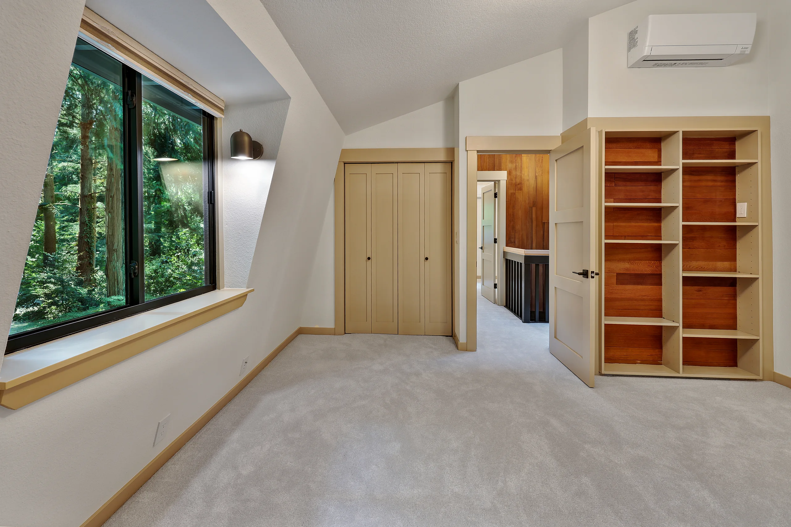 Bedroom with a large window facing the trees and built-in storage