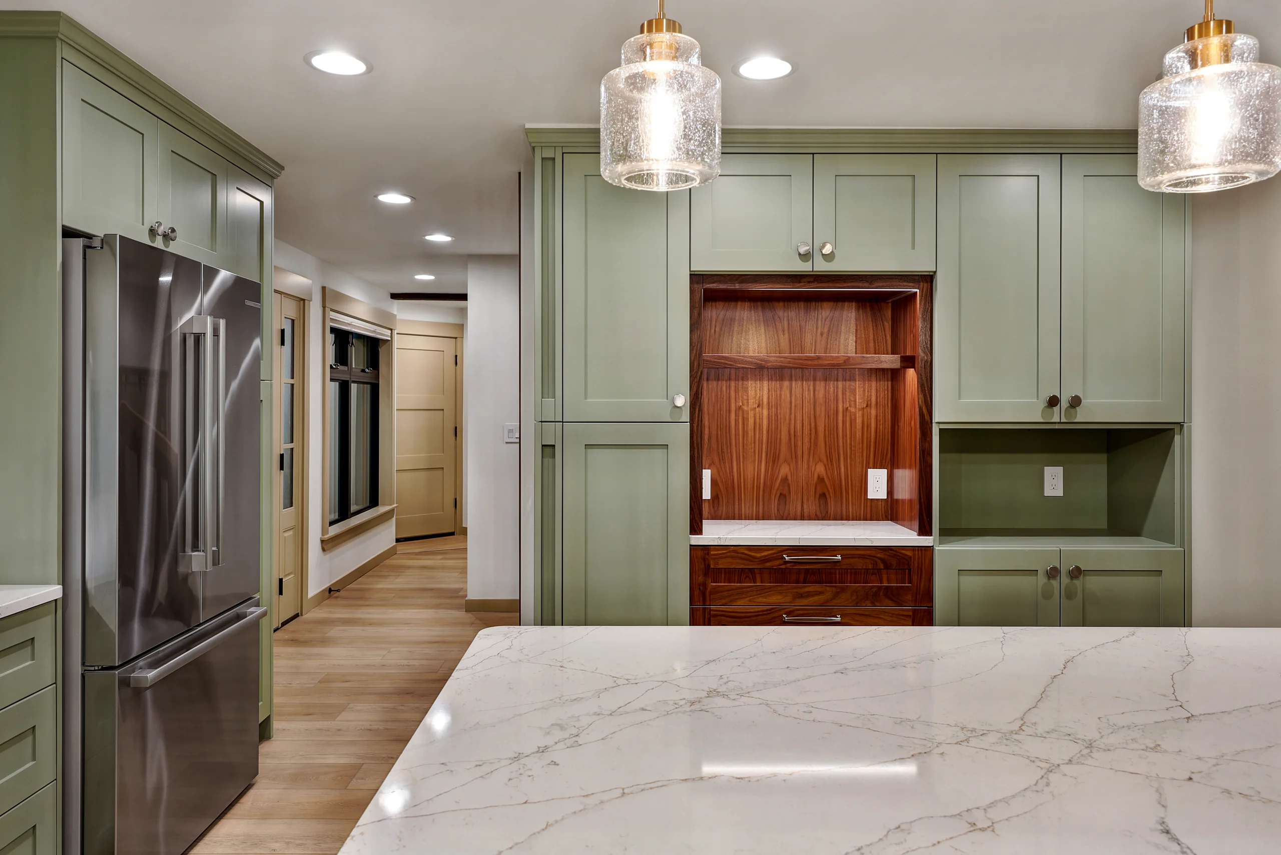 Kitchen cabinetry, wood panel detail, and pendant lights